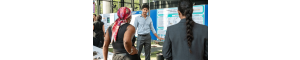 An image of a young male scientist pointing to a board as he presents a research poster at a science conference